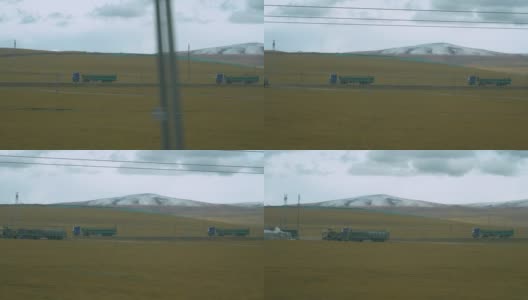 两辆大型货车在西藏平原的乡村公路上快速行驶。高清在线视频素材下载