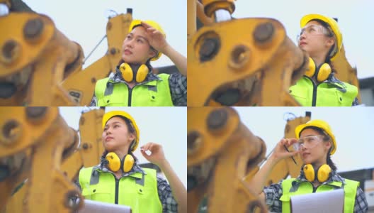 亚洲女工程师站在挖掘机的长柄勺旁，检查一个方案高清在线视频素材下载