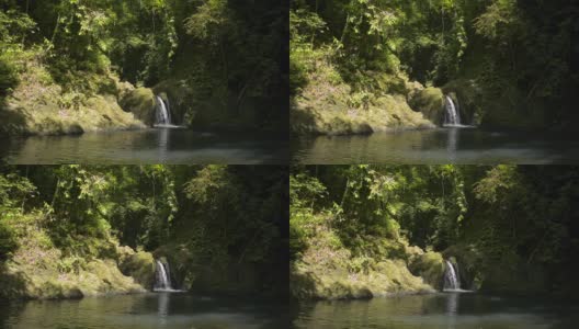 小瀑布流过群山。美丽的淡水在阳光下流入自然池塘在丛林。高清在线视频素材下载