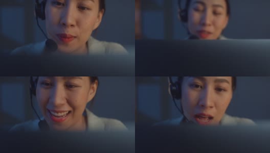 年轻的亚洲自由职业女性戴着耳机，晚上在家的客厅里用笔记本电脑进行视频会议和电话会议。高清在线视频素材下载