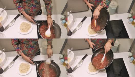 一名孕妇正在厨房里用红酱准备意大利面。高清在线视频素材下载