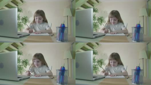 用笔记本电脑做作业。专注的小可爱的孩子在桌子上学习做家庭作业高清在线视频素材下载