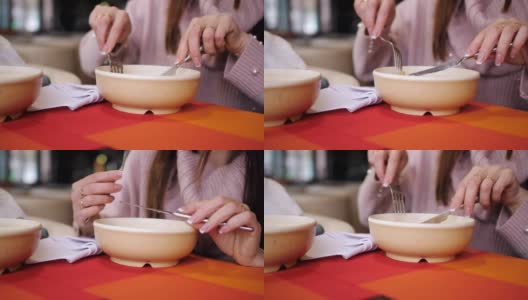 特写一盘饺子在餐厅里，一个女孩用刀叉吃着热饺子。高清在线视频素材下载