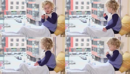 可爱的孩子吃食物，享受冬天的暴风雪窗外高清在线视频素材下载