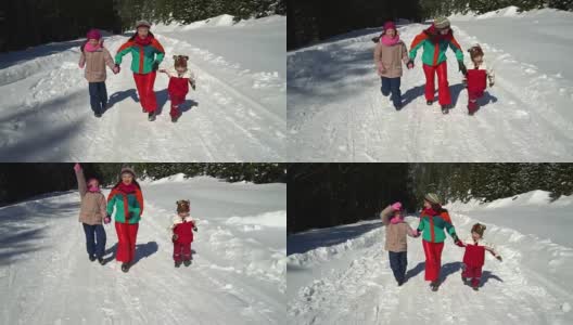 快乐的家庭在冬天的雪山森林里玩耍。妈妈和她的两个孩子。他们高兴地穿过雪地跑向照相机。高清在线视频素材下载