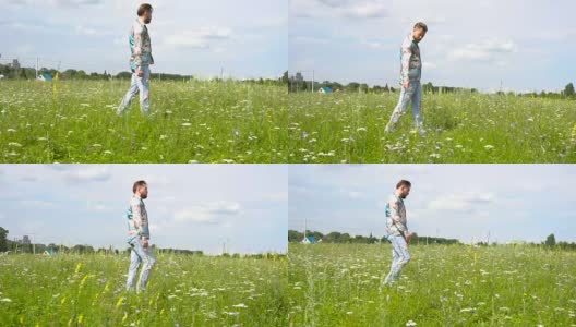 一个穿着破洞牛仔裤的英俊男子独自在草地上走来走去。高清在线视频素材下载