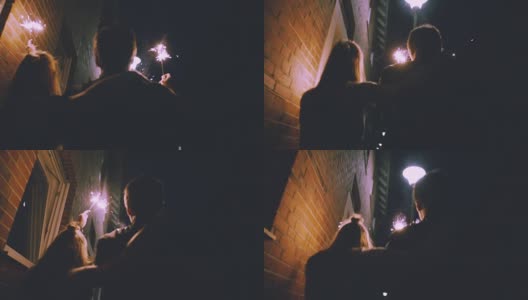 一对年轻夫妇晚上在城市的大街上拿着烟花高清在线视频素材下载