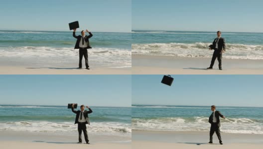 Happy businessman throwing his suitcase on the beach高清在线视频素材下载