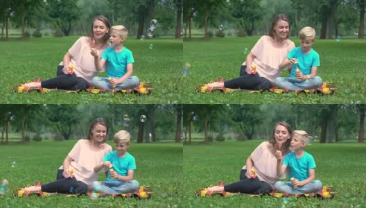 快乐的男孩吹泡泡，妈妈和儿子在公园玩，快乐的共同度假高清在线视频素材下载