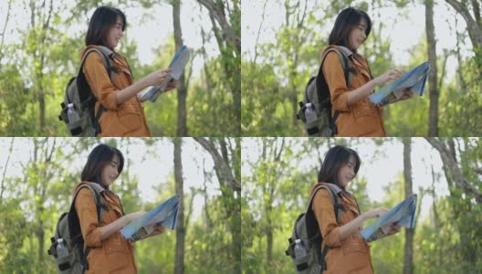 年轻的亚洲女性游客在阳光明媚的夏天走在森林里，查看纸质地图，享受度假的生活方式。高清在线视频素材下载