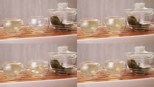 将中国绿茶从玻璃茶壶倒入一个小杯子中高清在线视频素材下载