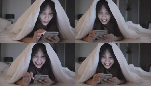 年轻的亚洲女子享受在床上使用智能手机的场景高清在线视频素材下载