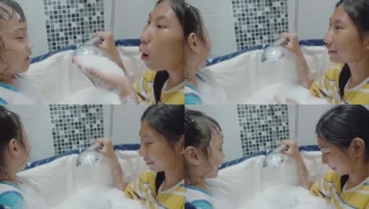 快乐的亚洲孩子们在塑料浴缸里对着姐姐的脸吹泡泡，生活理念。高清在线视频素材下载