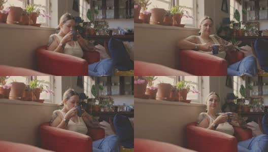一名年轻女子在家里的沙发上放松地喝咖啡的4k视频片段高清在线视频素材下载