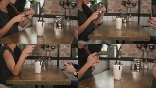 男男女女在用手机拍一杯奶昔，上面放着樱桃，在咖啡馆的木桌上放着稻草高清在线视频素材下载