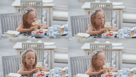可爱的小女孩在户外咖啡厅吃早餐高清在线视频素材下载