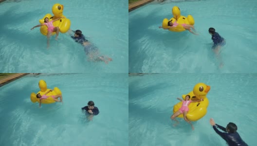 快乐的亚洲儿童在度假期间与家人在酒店或度假胜地一起在泳池中玩黄鸭橡皮艇，生活理念。高清在线视频素材下载