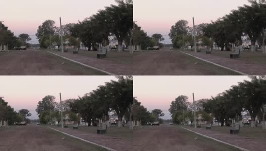 阿根廷恩特雷里奥斯省的一个小村庄里，日落时分，土路旁的一个空公园里有石凳。高清在线视频素材下载