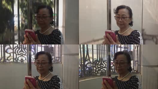 一位年长女性在电梯里使用智能手机高清在线视频素材下载