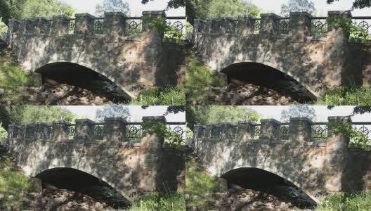 在一个晴朗的夏日，公园里的石桥在一条干涸的小溪上高清在线视频素材下载
