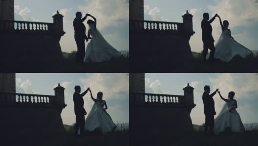 一对可爱的新婚夫妇在古老的城堡附近一起跳舞。轮廓高清在线视频素材下载