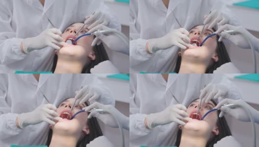 亚洲女牙医在牙科诊所用一名探险家检查年轻女孩的牙齿。牙科助理在治疗过程中协助医生使用吸痰器保持病人口腔干燥高清在线视频素材下载