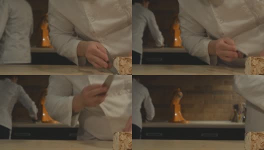 糖果师夫妇在糕点店工作。一名男子将奶油涂在蛋白酥皮卷上，背景中的一名女子用餐巾擦桌子，以保持清洁高清在线视频素材下载