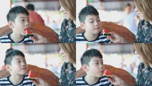 快乐的亚洲孩子与母亲喜欢吃熟西瓜。高清在线视频素材下载