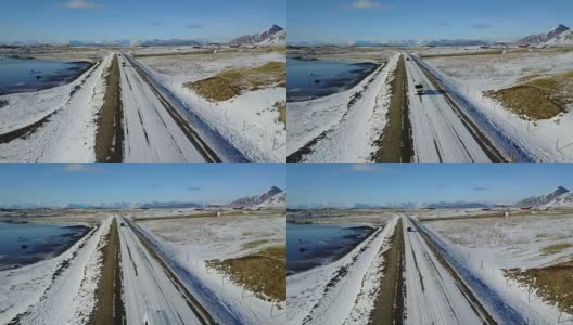 在冰岛东海岸的冬季，飞过冰雪覆盖的道路和雪山景观高清在线视频素材下载