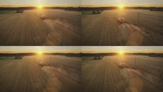 无人机拍摄的联合收割机在日落时分在田里工作。高清在线视频素材下载