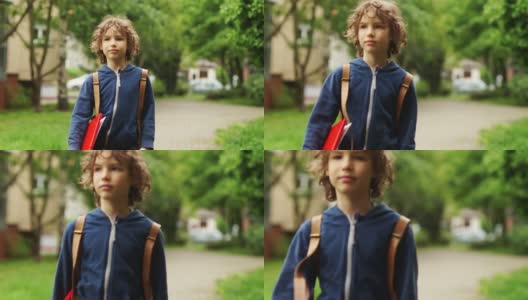 一个10-11岁男孩放学回家的肖像。在他身后，他背着一个背包，手里拿着一个红色文件夹。他脸上的表情严肃而专注高清在线视频素材下载