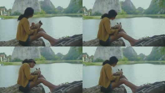 一个年轻女子和一只猫坐在一块石头上高清在线视频素材下载