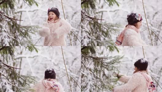 冬天的森林里，一个美丽的女孩在雪地里快乐。她穿着一件粉红色的外套，戴着手套和一顶黑色的帽子高清在线视频素材下载