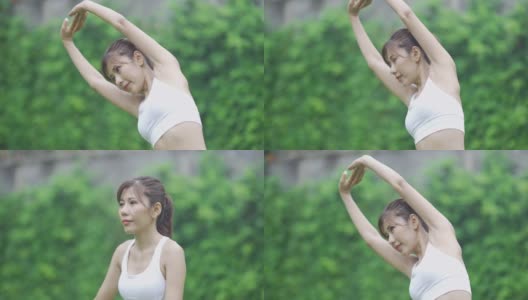 亚洲妇女穿着运动服，在草坪上锻炼手臂高清在线视频素材下载