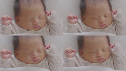 特写快乐的新生儿躺在白色的毯子上睡觉，舒适和安全。可爱的亚洲新生儿在床上睡觉和打盹。新生儿摄影理念高清在线视频素材下载