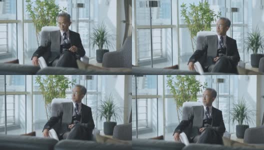 成功的亚洲华人CEO商人坐在办公室休息室看着别处高清在线视频素材下载