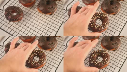 烤架上的甜甜圈涂上巧克力奶油或糖霜。女人手里放了一个甜甜圈高清在线视频素材下载