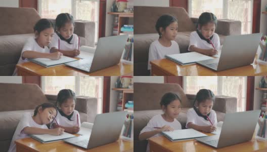 两名亚洲女童学生通过视频一起与老师在线学习。由于Covid - 19大流行，兄弟姐妹在隔离期间用电脑在家学习。高清在线视频素材下载