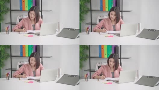专注专注的亚洲女商人专业工作者写笔记规划思维创意创意策略，员工努力工作在现代办公室使用笔记本电脑技术高清在线视频素材下载