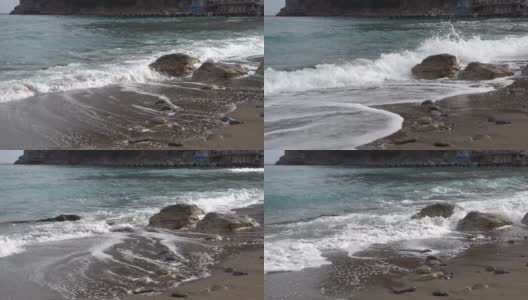 在克里米亚的诺维斯韦(Novy Svet)村的荒芜沙滩上，一股纯净的黑海海浪拍打着一块石头。早春多云高清在线视频素材下载