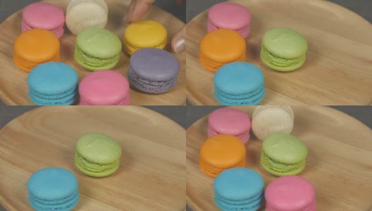 一个女人用4k的手挑选桌上五颜六色的马卡龙甜点高清在线视频素材下载