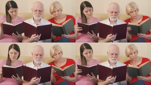 一对老年夫妇和十几岁的女儿在看纸质书。传统古典读本的概念高清在线视频素材下载