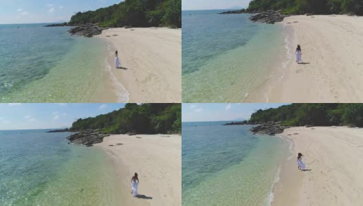 一个穿着白色裙子的女孩正沿着海边跑步。高清在线视频素材下载