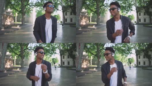 年轻时髦的黑人男子戴着白色耳机和太阳眼镜在市中心的户外跳舞，玩得很开心高清在线视频素材下载