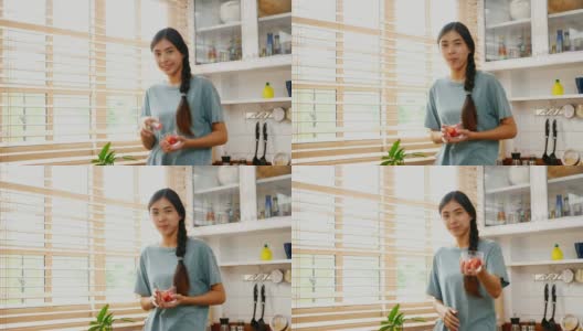 年轻的亚洲女人在家里的厨房里吃着幸福的草莓，人们健康的生活方式高清在线视频素材下载