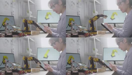 女工程师正在他的车间里研究创新技术机械机器人手臂，她用数字平板电脑用手控制机器人手臂高清在线视频素材下载