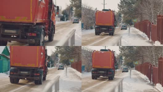 一辆载着沙子的卡车在白雪覆盖的街道上行驶。后面的观点。缓慢的运动。清洁服务高清在线视频素材下载