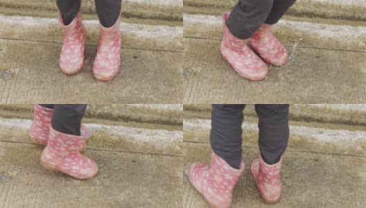 小女孩在水滴飞溅的水坑上跳着，近距离拍摄了4K大小的靴子和鞋子，在城市街道上展示了孩子们雨后的户外活动，快乐和享受。高清在线视频素材下载