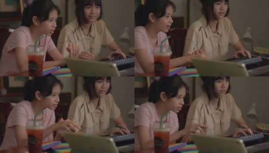 两个可爱的亚洲少女喜欢在家里用电脑键盘和数码设备玩在线视频游戏。年轻玩家与朋友交流互动的直播，高清在线视频素材下载