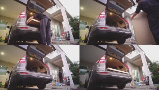 亚洲人正把一个纸箱从汽车后备箱搬到新房子里高清在线视频素材下载